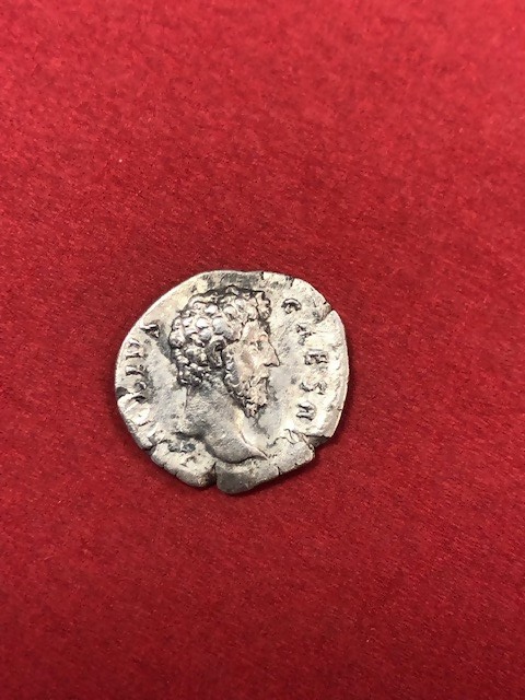 Eine Silbermünze mit dem Konterfei eines bärtigen Mannes und einzelnen Buchstaben und Ziffern liegt auf einem roten Untergrund. (verweist auf: Antike Münzen an Bulgarien zurückgegeben)